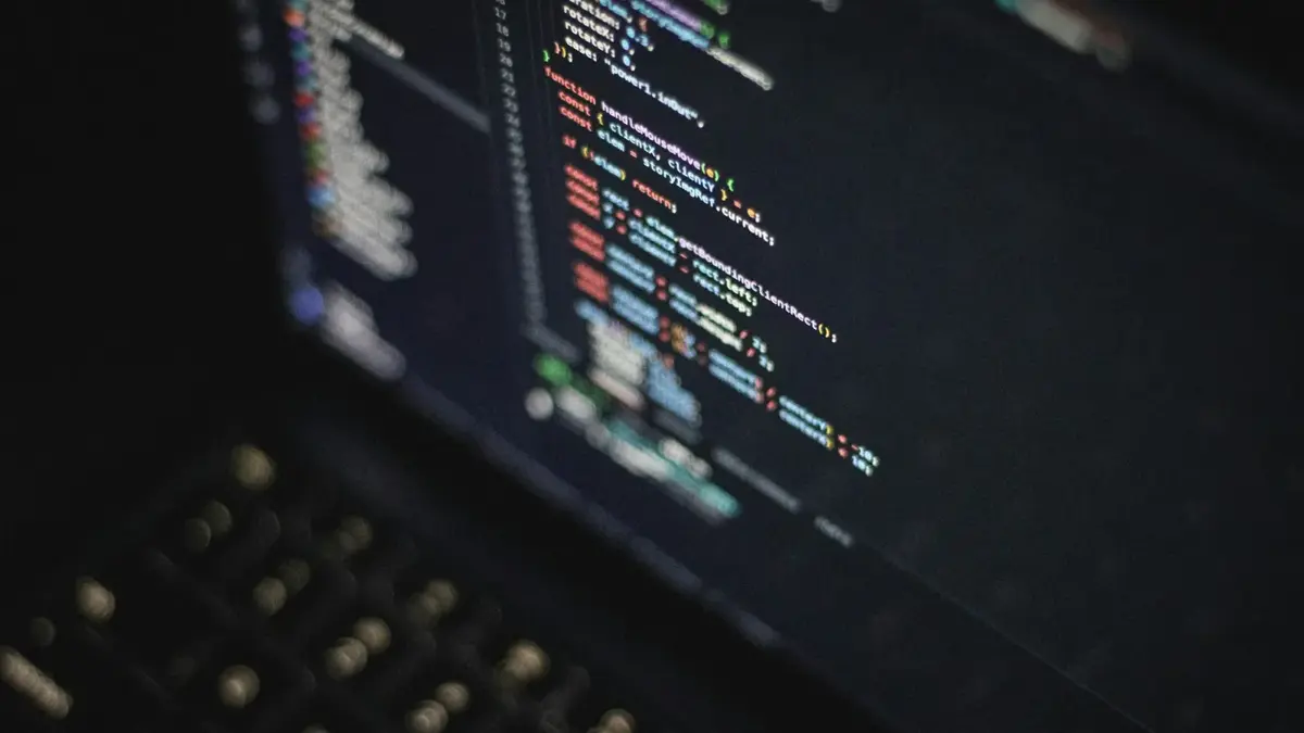 Close-up of colorful JavaScript source code on a dark laptop screen beside a keyboard