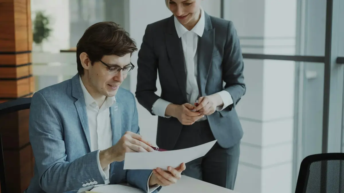 Two colleagues reviewing printed documents together at an office desk