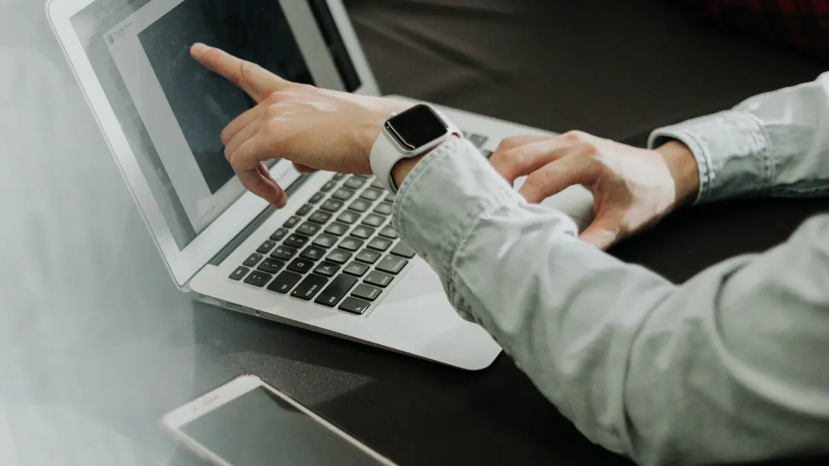 Two colleagues reviewing a laptop screen with a phone on the table