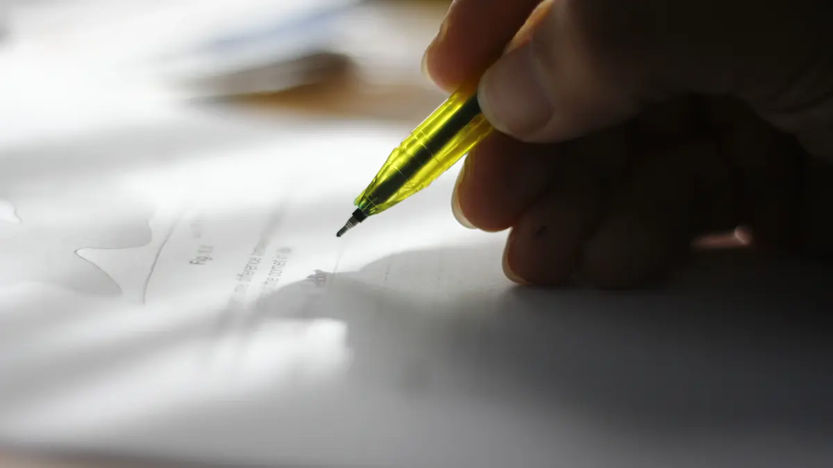 A hand holding a translucent green mechanical pencil above a printed document